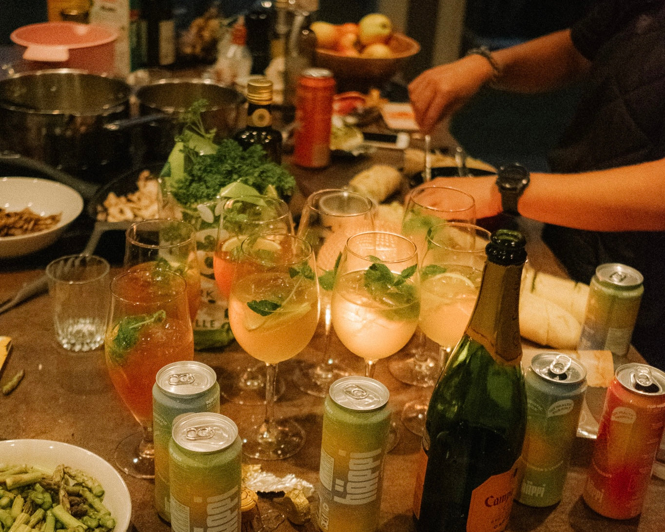 A cozy gathering with a table full of vibrant hÄppi prebiotic sodas, fresh ingredients, and cocktails garnished with mint, showcasing a lively and healthy social setting perfect for shared moments.