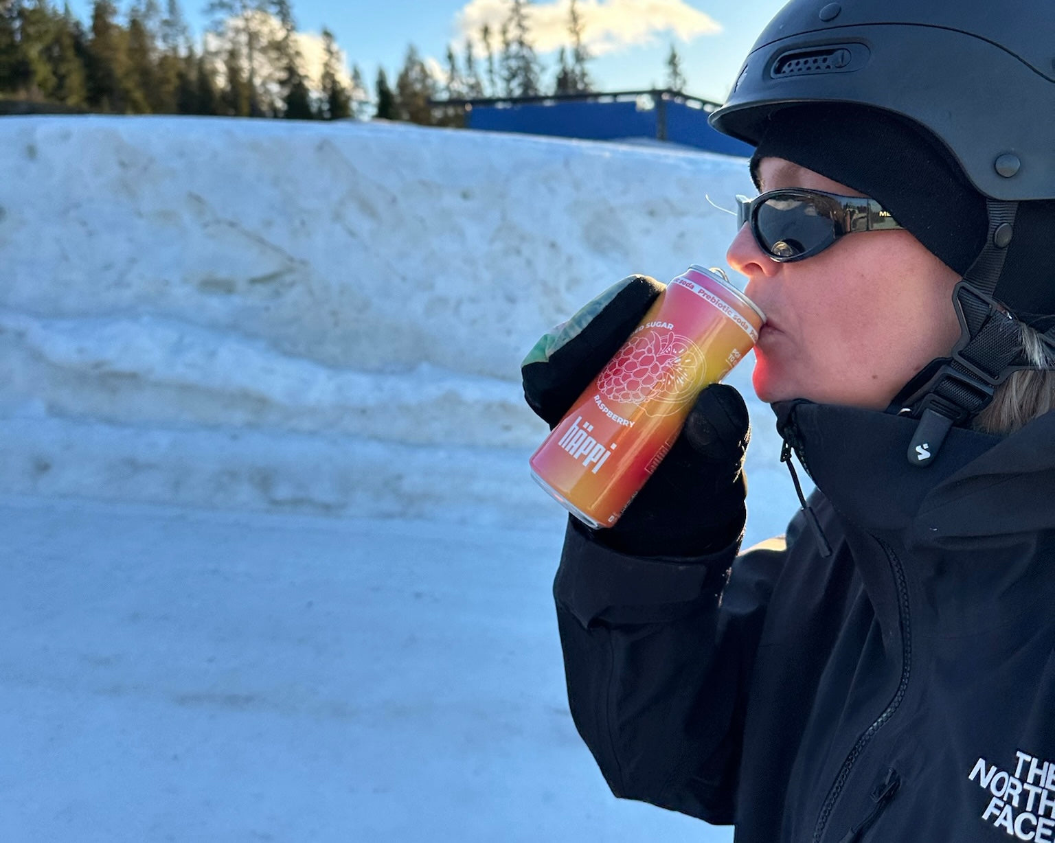 A person in winter gear enjoys a refreshing hÄppi prebiotic soda in a snowy outdoor setting, highlighting the perfect healthy drink for active, cold-weather adventures.