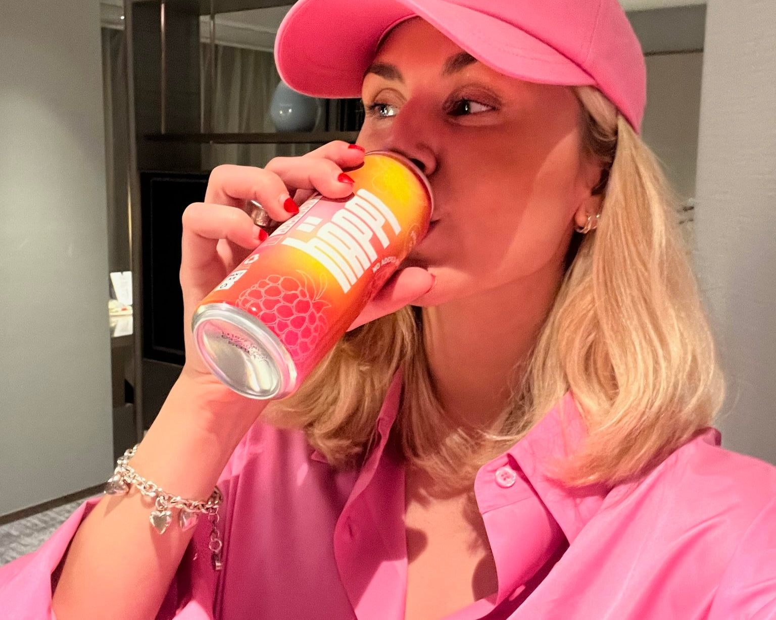 Woman in pink drinks häppi prebiotic soda, boosting gut health with a refreshing, immune-boosting beverage.